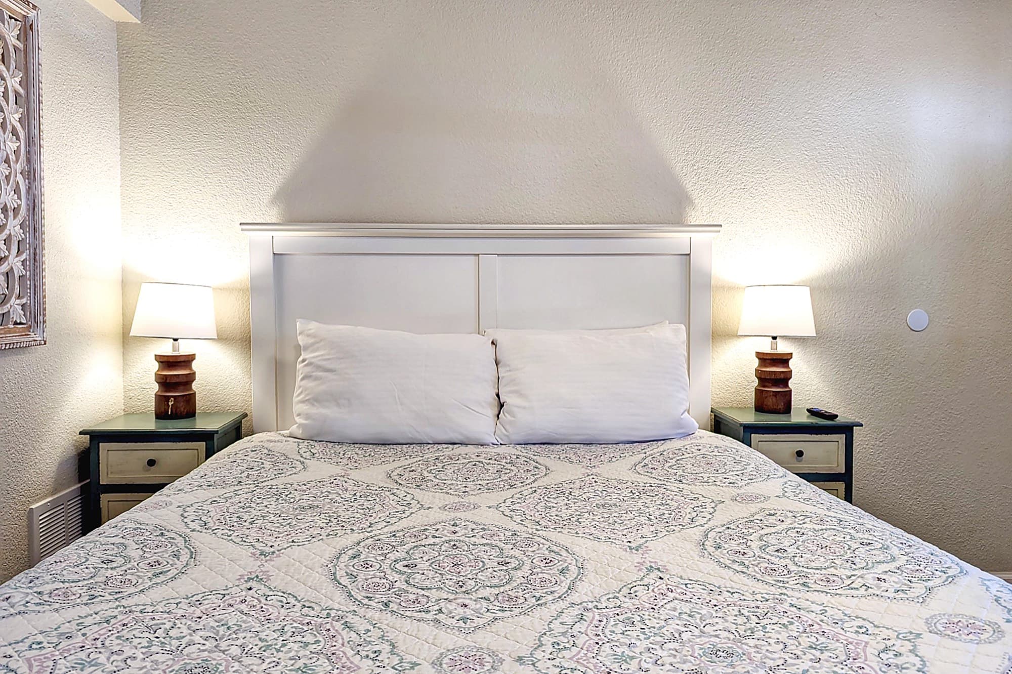 A queen room with a made bed and bedside lamps